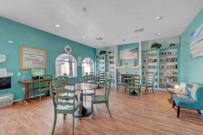 Inviting community room featuring chic turquoise walls, ample seating, and well-stocked bookshelves, perfect for reading and relaxing.