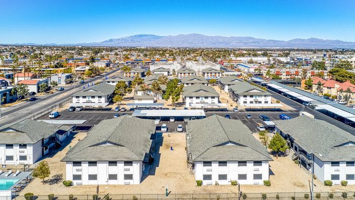 Aerial view of a charming suburban apartment complex with neatly arranged buildings, ample parking, and scenic mountain backdrop.