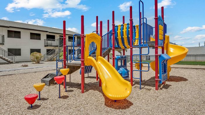 Vibrant playground with colorful slides and climbing structures in a sunny apartment community, perfect for family fun and active living.
