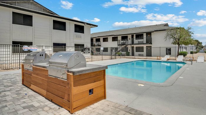Inviting outdoor pool area with modern barbecue grills and comfortable lounging chairs, perfect for sunny days.