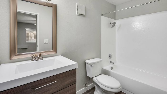 Modern bathroom featuring a sleek vanity with elegant mirror, pristine bathtub, and contemporary faucet in a stylish setting.