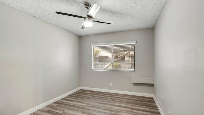 Bright, cozy bedroom with modern ceiling fan and large window letting in natural light, perfect for a serene living space.
