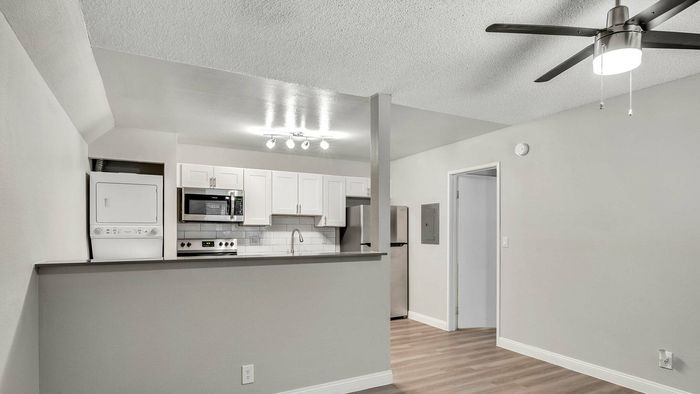 Modern kitchen with sleek white cabinets, stainless steel appliances, and in-unit laundry in a bright open space.