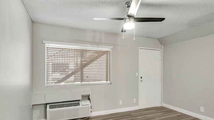 Bright and airy room with modern ceiling fan and large window featuring stylish blinds, perfect for a cozy and inviting living space.