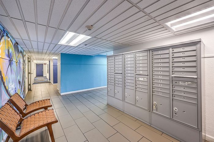 Modern apartment lobby with vibrant mural, stylish seating, and sleek mailboxes for convenient living.