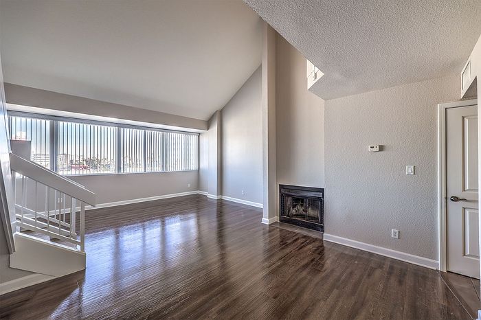 Spacious apartment living area with elegant high ceilings, large windows, and a cozy fireplace.
