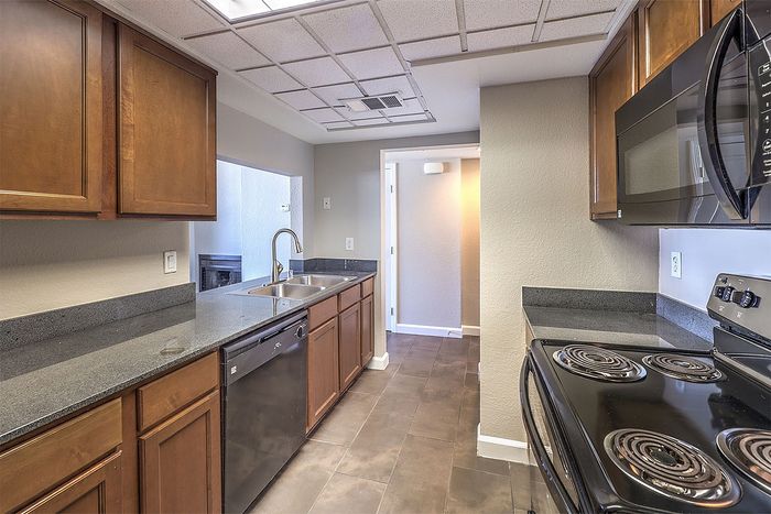 Modern kitchen with sleek countertops, warm wooden cabinetry, and stainless steel appliances, offering a spacious and inviting cooking area.