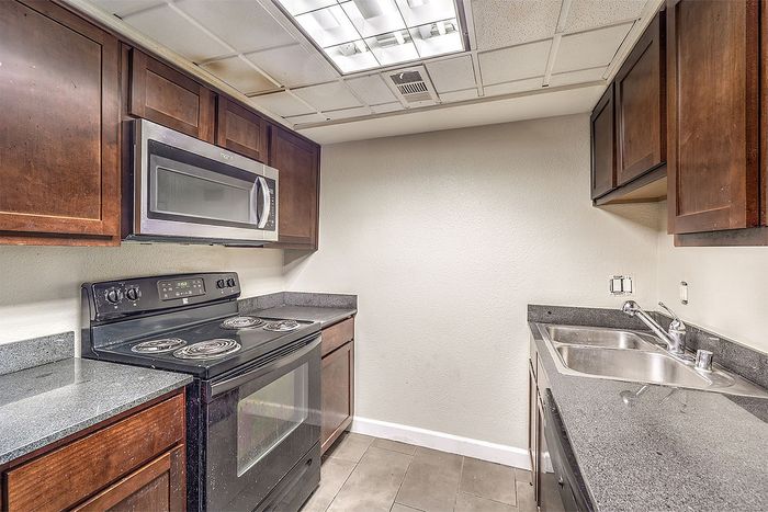 Modern kitchen with sleek countertops, stainless steel appliances, and rich wooden cabinetry.