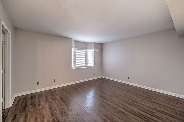 Spacious room with elegant wood flooring and large windows offering abundant natural light.
