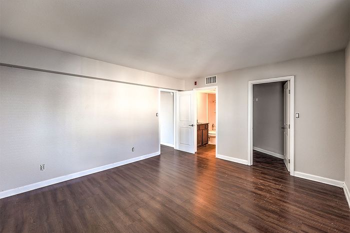 Spacious modern apartment with sleek hardwood floors and bright natural lighting, featuring an airy open layout and inviting neutral tones.