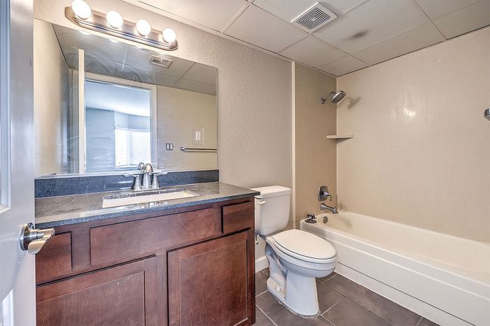 Elegant bathroom with sleek granite countertop, modern lighting, and a pristine bathtub setup.