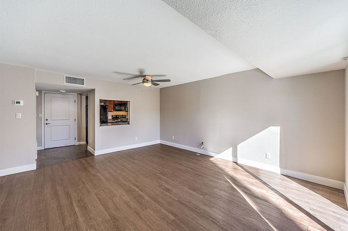 Bright, modern living space featuring elegant hardwood flooring, recessed lighting, and an open pass-through to a stylish kitchen.
