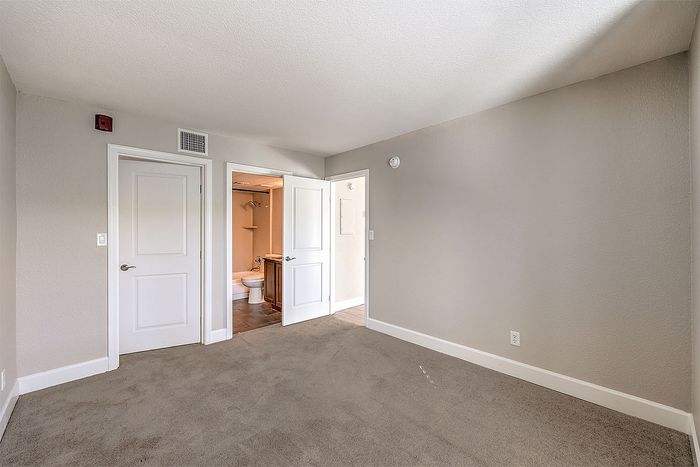 Bright and spacious bedroom with plush carpeting and access to a modern en-suite bathroom.