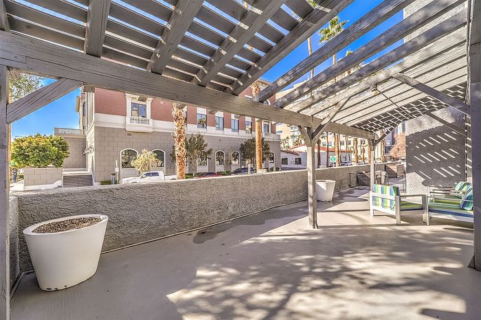 Charming outdoor patio with a stylish pergola and cozy seating in a vibrant urban setting.