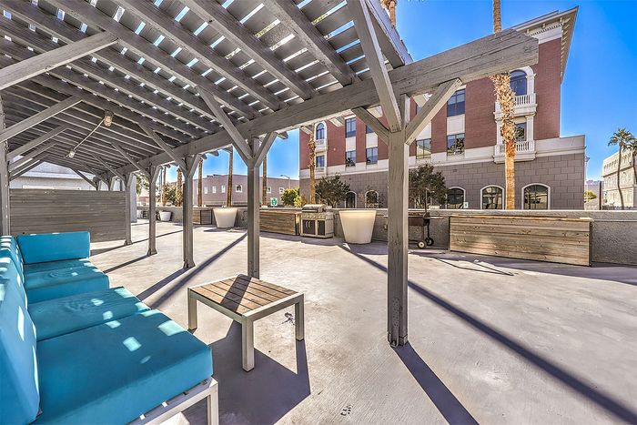 Chic outdoor patio with modern pergola and vibrant seating, perfect for relaxing or entertaining.