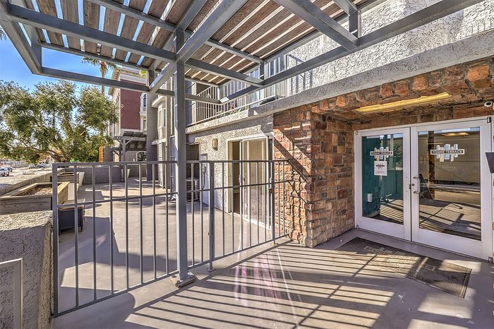 Inviting apartment entrance with modern pergola and rustic stone accents, offering a welcoming outdoor space.