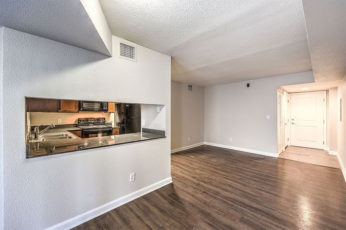Modern apartment interior with sleek hardwood floors, a bright open layout, and a stylish kitchen featuring stainless steel appliances.