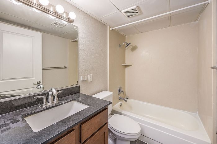 Elegant bathroom with sleek granite countertop, modern fixtures, and a cozy bathtub for ultimate relaxation.