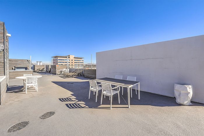 Expansive rooftop terrace with modern outdoor furniture and stunning city views under a clear blue sky.