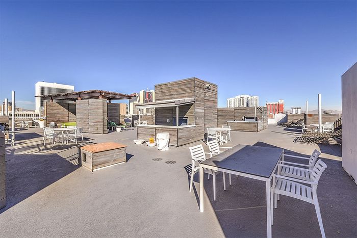Modern urban rooftop terrace featuring stylish wooden structures, chic seating areas, and panoramic city views.