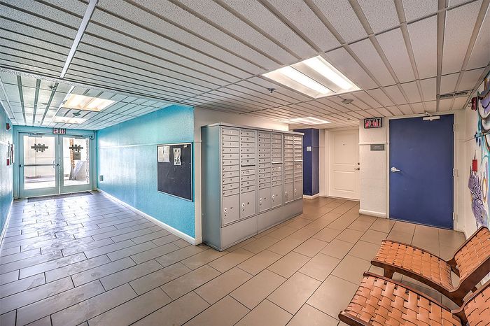 Modern apartment hallway with bright blue walls, secure mailboxes, and stylish seating area, offering a welcoming entrance.