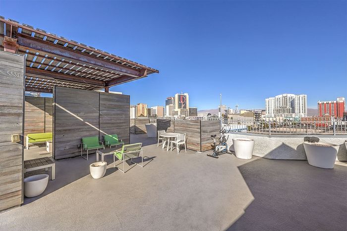 Rooftop lounge with stylish green seating, modern pergola, and panoramic city views, perfect for urban relaxation.