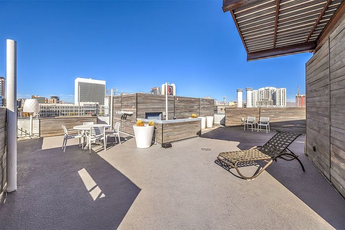 Modern urban rooftop patio with stylish seating, perfect for relaxation and city views, featuring sleek design and bright blue skies.