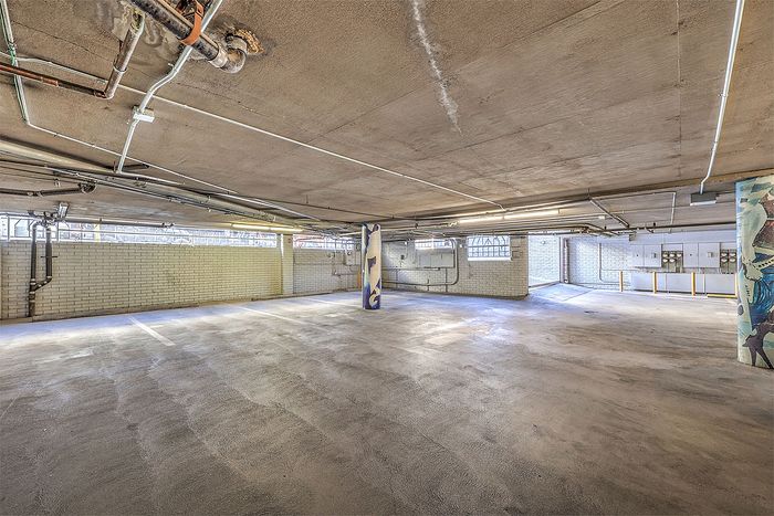 Spacious and well-lit underground parking garage with clean concrete flooring and stylish mural accents.