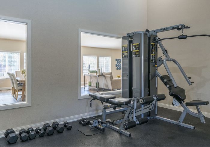 Modern gym with state-of-the-art equipment, bright interiors, and seamless access to a cozy living area through large windows.