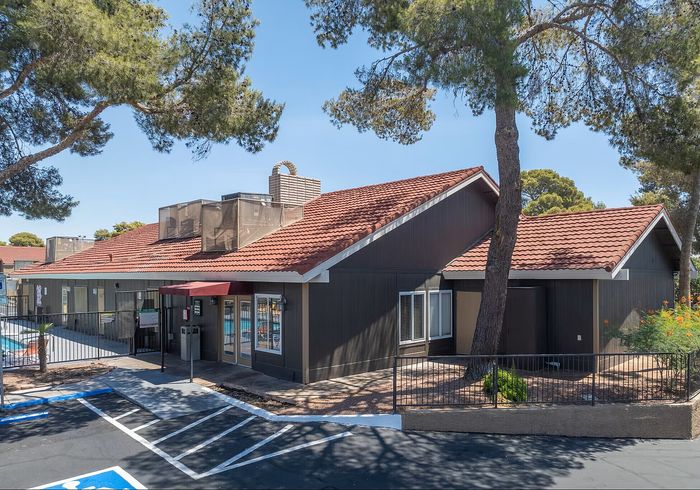 Charming residential building with red-tiled roof and lush greenery, offering a serene and inviting atmosphere.
