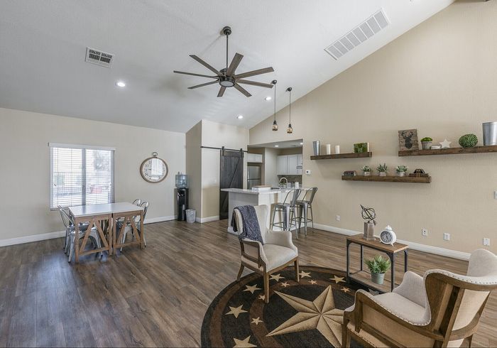 Contemporary open-concept living space featuring stylish hardwood floors, cozy seating area with unique star-themed rug, dining area with natural light, and a modern kitchen with pendant lighting.