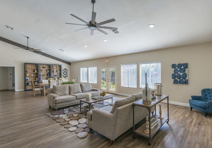 Spacious and stylish living room with modern decor showcasing a comfortable seating area, elegant wooden flooring, and abundant natural light from large windows.