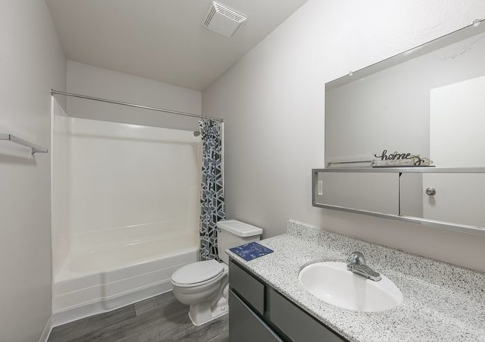 Modern bathroom with sleek granite countertop, elegant mirror, and bright lighting, offering a fresh and inviting atmosphere.