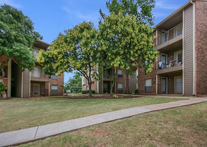 Charming apartment community with lush greenery, inviting pathways, and spacious balconies.