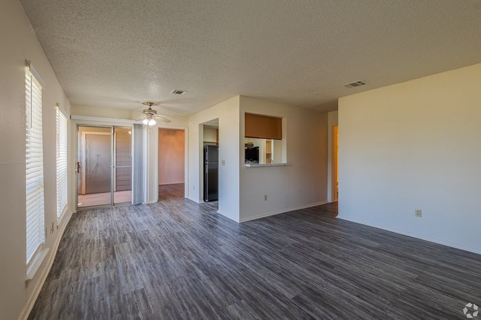 Spacious apartment living area featuring sleek hardwood floors, bright natural light, and access to a private balcony.