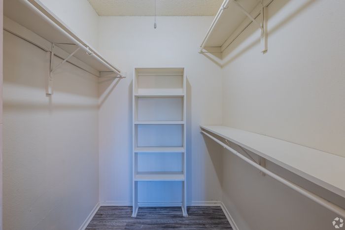 Spacious walk-in closet with ample shelving and stylish laminate flooring, ideal for maximizing storage and organization.