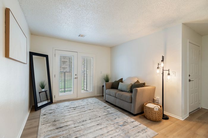 Charming living room with cozy sofa, stylish floor lamp, and elegant decor, featuring natural light through glass doors.