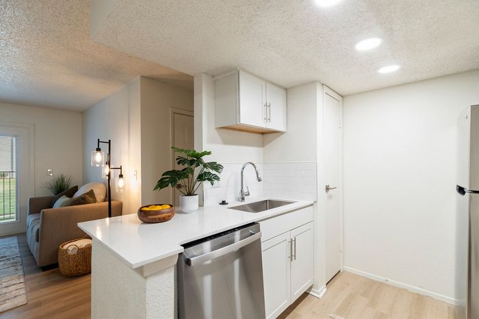Modern kitchen with sleek white cabinetry, stainless steel appliances, and open living area, perfect for cozy gatherings.