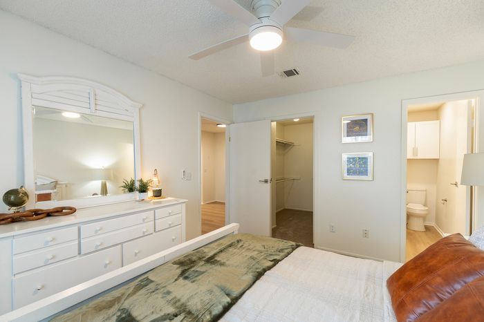 Inviting bedroom with elegant white dresser, cozy bed, and a spacious walk-in closet for ample storage.