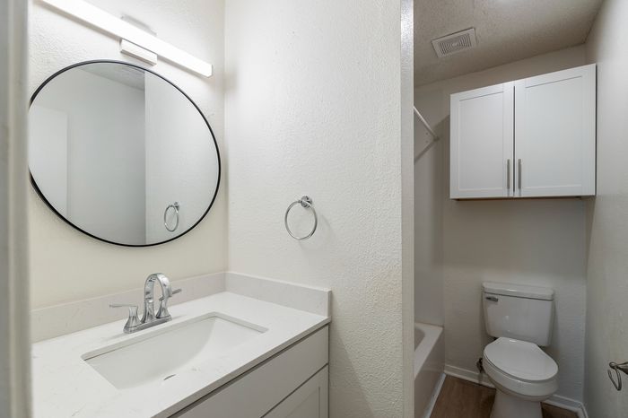 Modern bathroom featuring a sleek vanity with a round mirror, elegant lighting, and ample cabinet space.