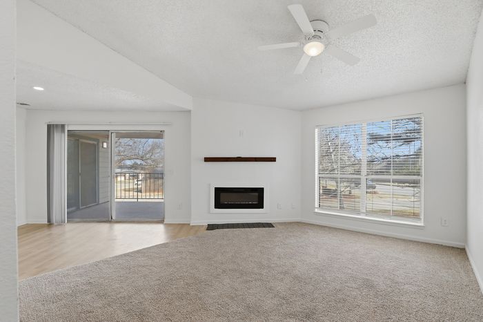 Bright and airy living room with a modern fireplace, large windows, and access to a spacious balcony.