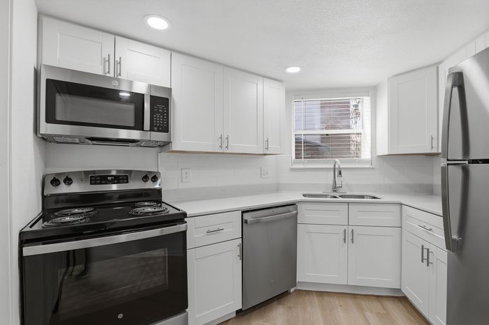 Modern kitchen with sleek stainless steel appliances, white cabinetry, and ample natural light.