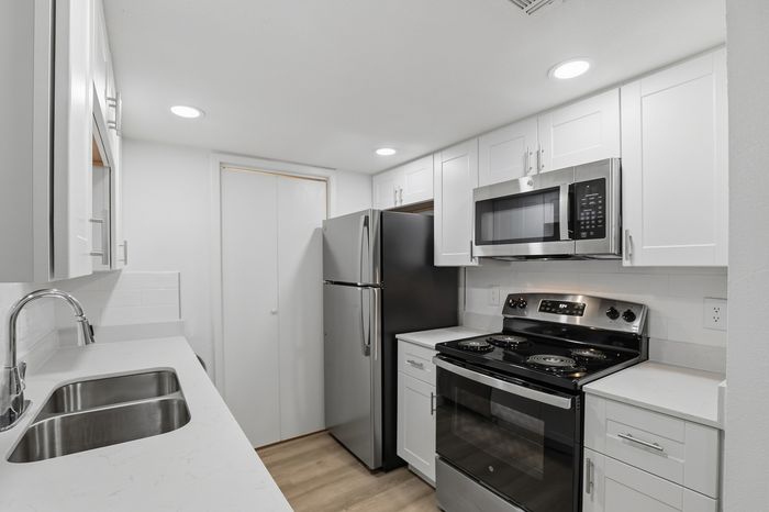 Modern kitchen with sleek stainless steel appliances, elegant white cabinetry, and a stylish double sink, offering a bright and functional culinary space.