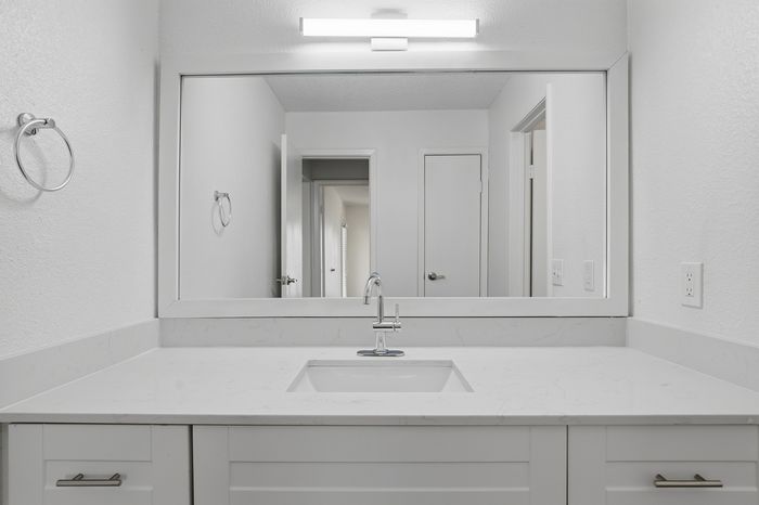 Modern bathroom vanity with sleek design, large mirror, and elegant white countertop.