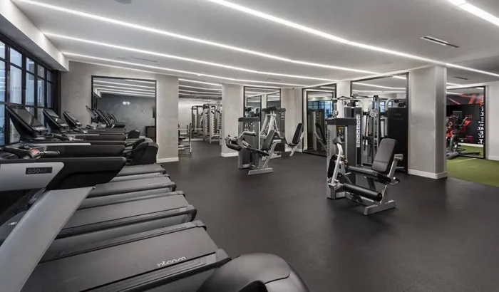 Treadmills and weight stations with mirrored HIIT area in background at Modera San Diego apartments.