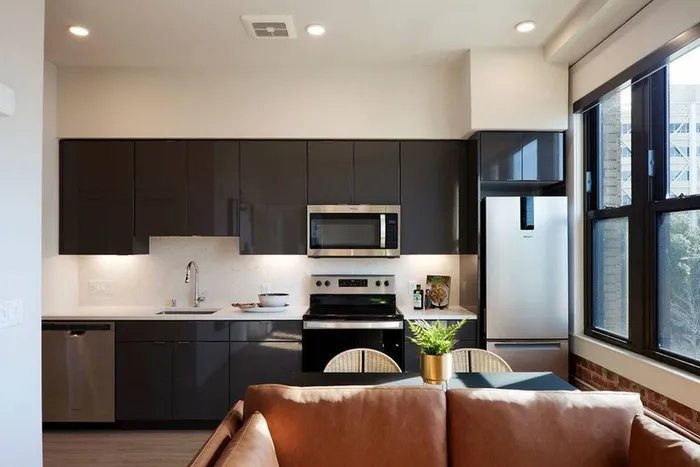 View of kitchen with large windows letting in plenty of light above seating area and couch in a Modera Berkeley apartment.