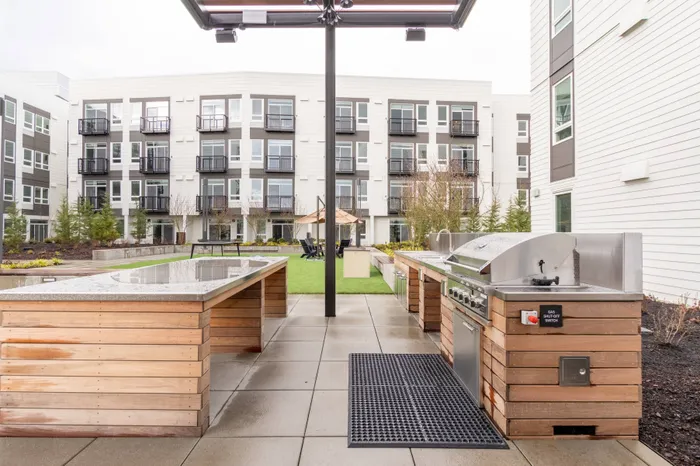 Large grilling area with ample prep space and wooden details  at Modera River Trail apartments.