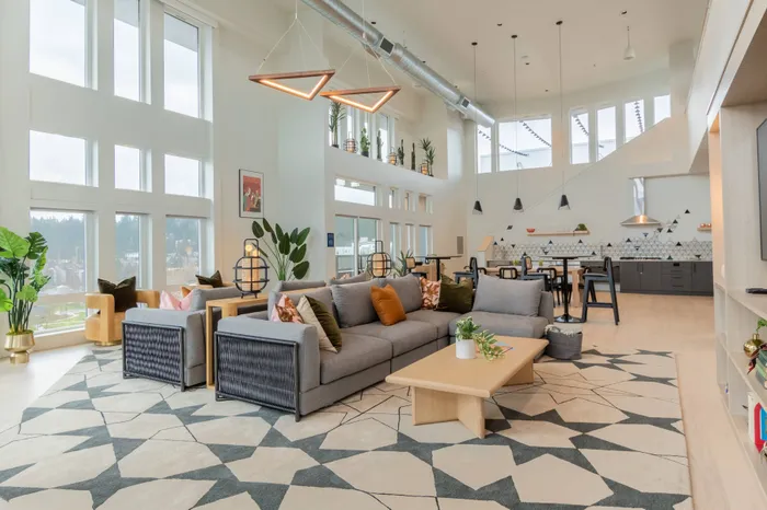 Large couch and kitchen in common area at Modera River Trail.