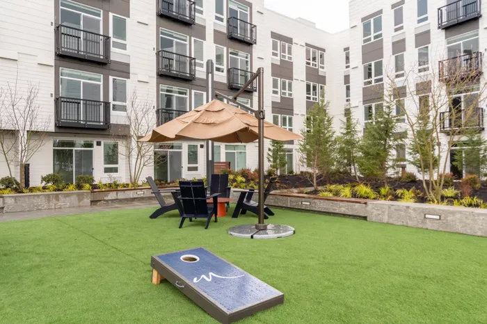 Courtyard with greenery, cornhole and seating area  at Modera River Trail apartments.