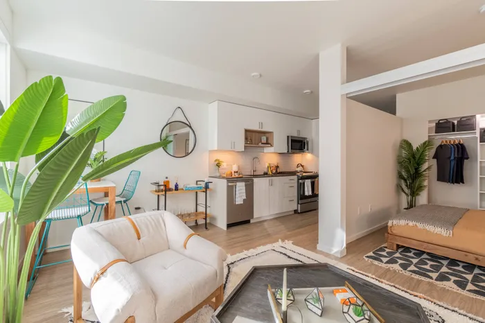 Living room, view of bedroom and galley-style kitchen all styled in a boho-chic decor in an apartment at Modera River Trail.